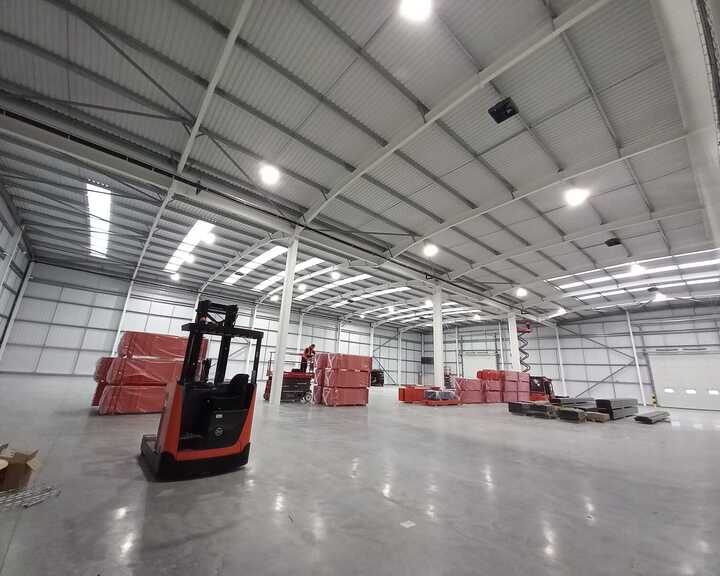 Empty industrial warehouse with a forklift and stacks of red pallets.