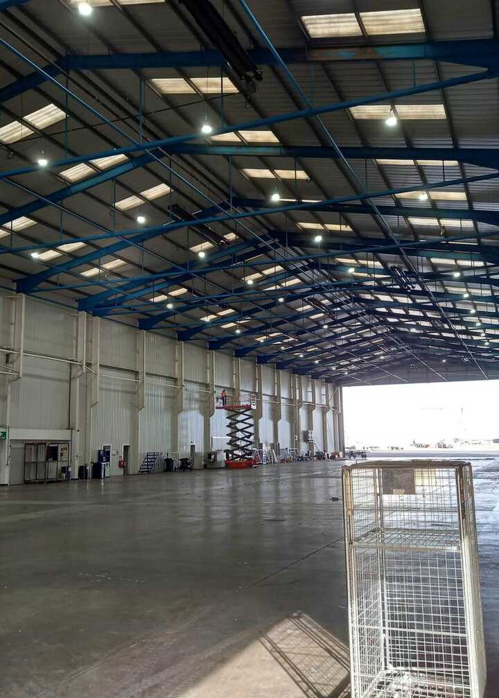 Sign for Rhenus Logistics on a green wall, with a light fixture below it.