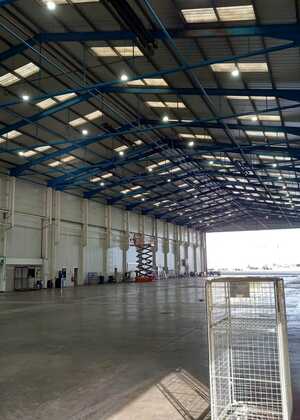 Sign for Rhenus Logistics on a green wall, with a light fixture below it.