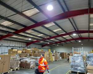 Interior of a warehouse with pallets and a worker in a safety vest.