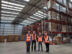 LEDLights4You team in safety vests stand in a warehouse with tall shelves of stacked boxes.