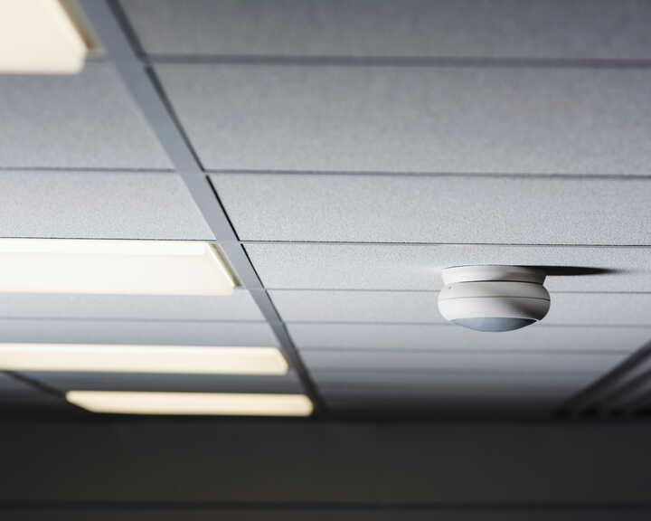 Ceiling tiles with fluorescent lights and a smoke detector.