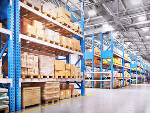 Warehouse interior with blue shelving units and stacked pallets of goods.