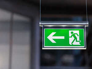 Green exit sign with an arrow pointing left and a person walking out.