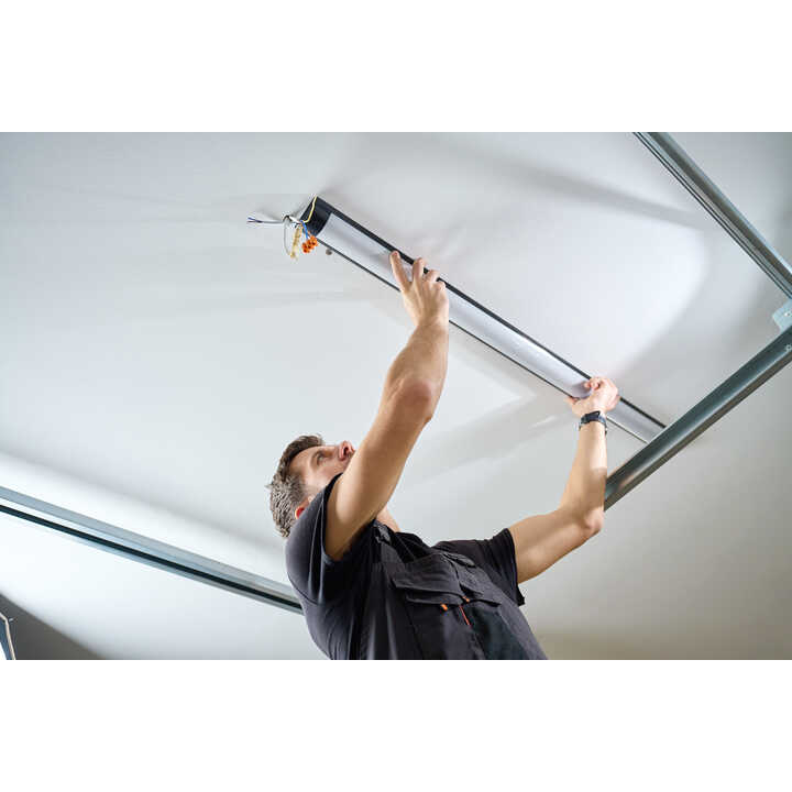 A person is installing a ceiling light fixture while looking up.