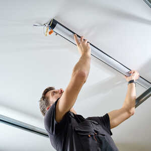 A person is installing a ceiling light fixture while looking up.