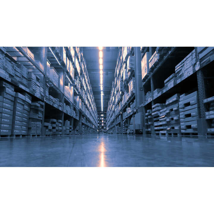 A wide angle view of a warehouse aisle with shelves stacked with pallets.