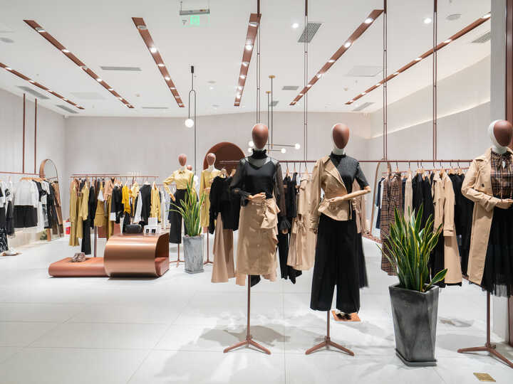 A modern clothing store interior with shelves and a mirror, featuring various garments.