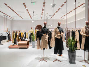 A modern clothing store interior with shelves and a mirror, featuring various garments.