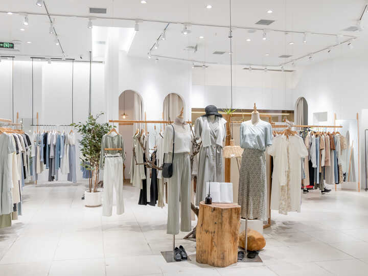 Modern clothing store interior displaying racks of apparel and a wooden display table.