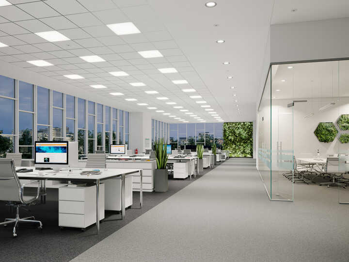 Modern office interior with desks, plants, and large windows.