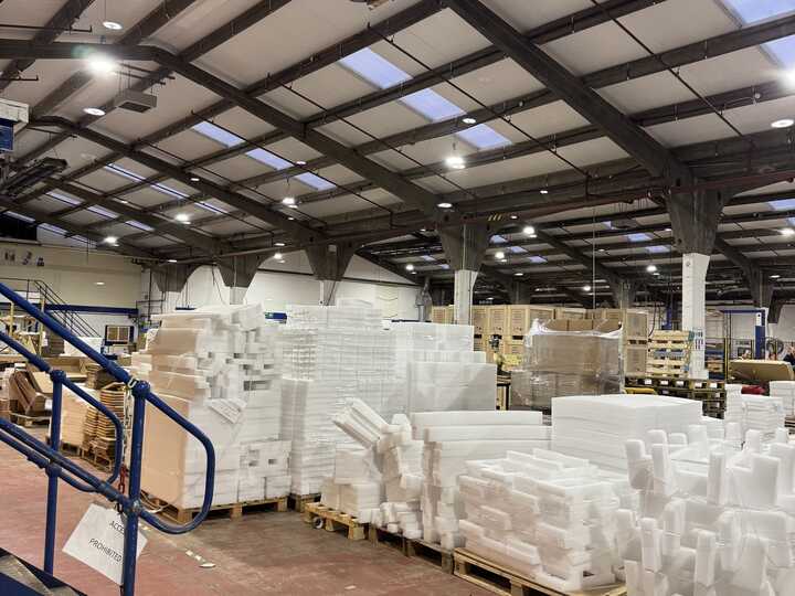Warehouse interior with blue shelving units and stacked pallets of goods.