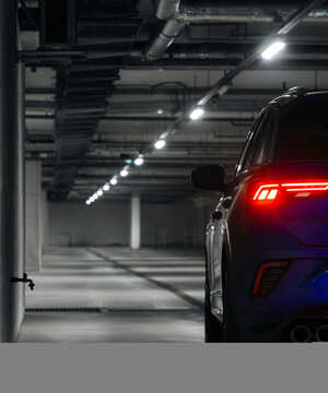 Car parked in a dimly lit garage, showing its rear lights and sleek design.