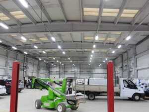 Interior of a spacious warehouse with various vehicles and machinery visible.