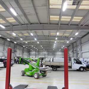 Newly lit warehouse interior with a green lift and several vehicles.