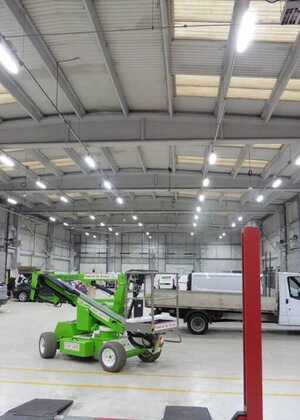 Interior of a spacious warehouse with machinery and vehicles.